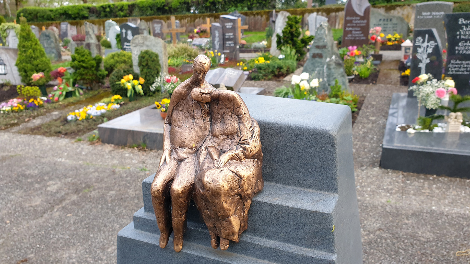 St. Peter: Skulptur auf einem Friedhof: Bronzenes Ehepaar sitzt auf einer Bank