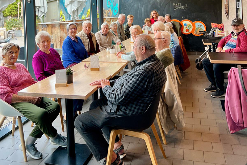 Bewohnerinnen und Bewohner des betreutes Wohnen sitzen im Café