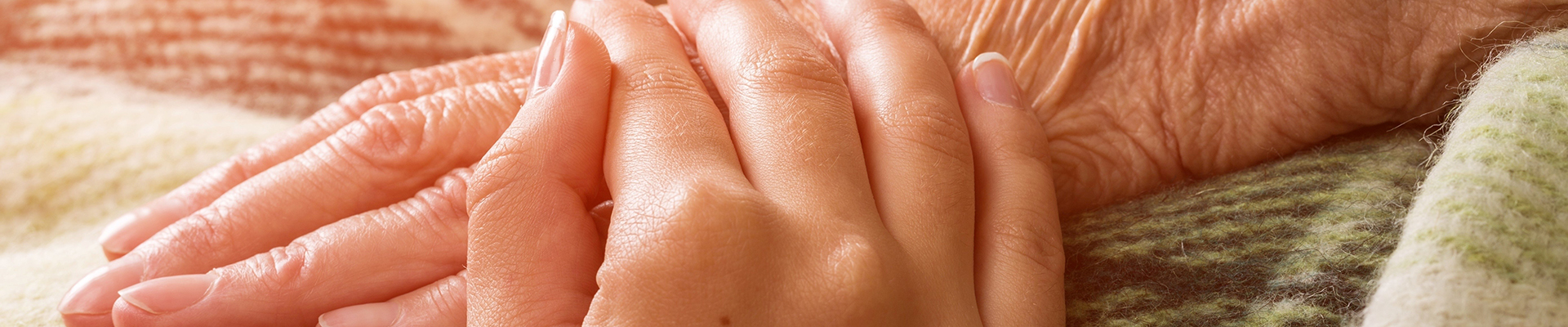 Hospizmitarbeiter hält die Hand eines Klienten