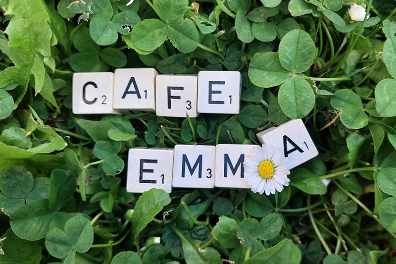 Café EMmA - Sozialstation Sachsenheim – Schriftzug mit Buchstaben-Würfel im Kleeblatt dargestellt